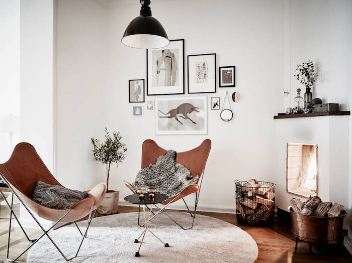 intérieur scandinave, lampe suspendue noire, mur de cadres art prints, tapis rond blanc, chaise papillon marron