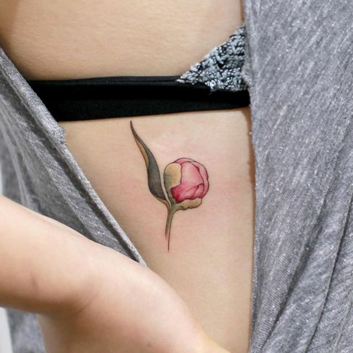 tatouage abstrait sur la côte, petit bouton rose de pivoine, tatouage discret et coloré
