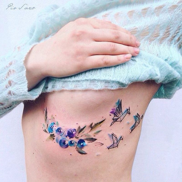 un tatouage aquarelle très poétique composé de grues en origami et une branche fleurie
