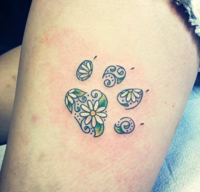 tatouage chat, marguerites et feuilles vertes dans les empreintes de pattes