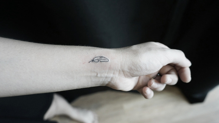 petit tatouage, dessin en encre sur le poignet, tatouage à design plume discret