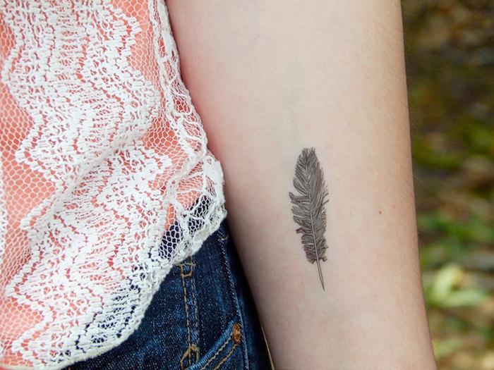tatouage femme, dessin en encre sur la peau, tatouage à motif plume, paire de jeans et t-shirt orange