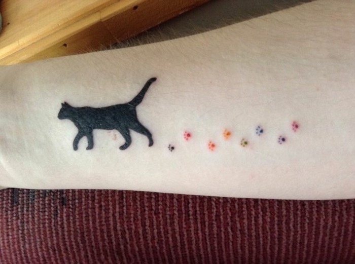 tatouage empreinte, pattes colorées et un chat noir marchant sur l'avant-bras