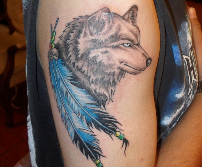 tatouage homme, dessin sur la peau avec loup et plumes bleues, tatouage sur l'épaule