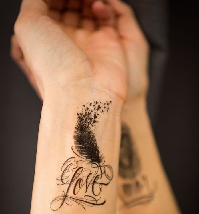 idée tatouage femme, dessin en encre sur le poignet, mot inspirant amour avec plumes et petits coeurs