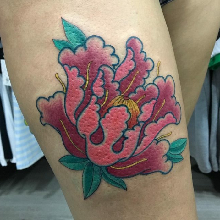tatouage fleur, pivoine tatoué à la jambe, centre jaune et feuilles autour de la corolle