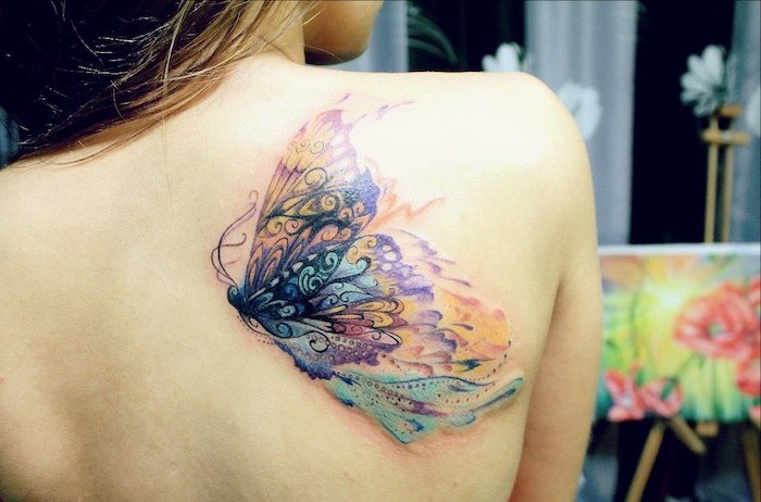 tatouage couleur, papillon multicolore à design aquarelle, femme cheveux balayage