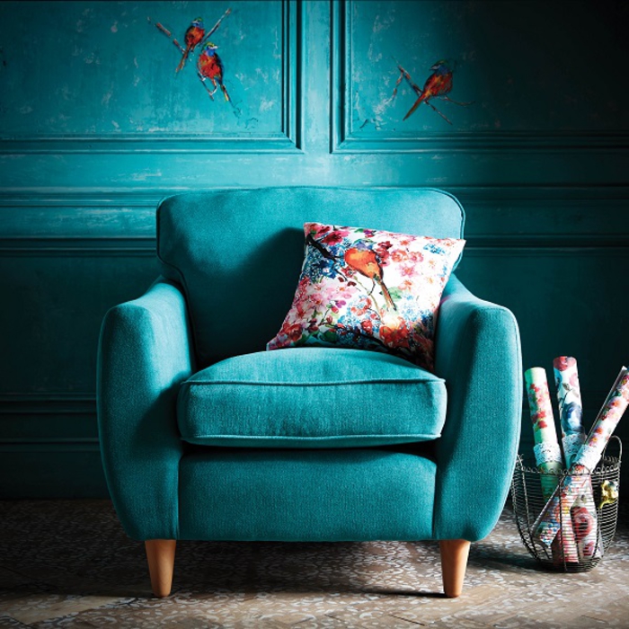 un fauteuil bleu sarcelle élégant associé à un coussin imprimé à motif floral