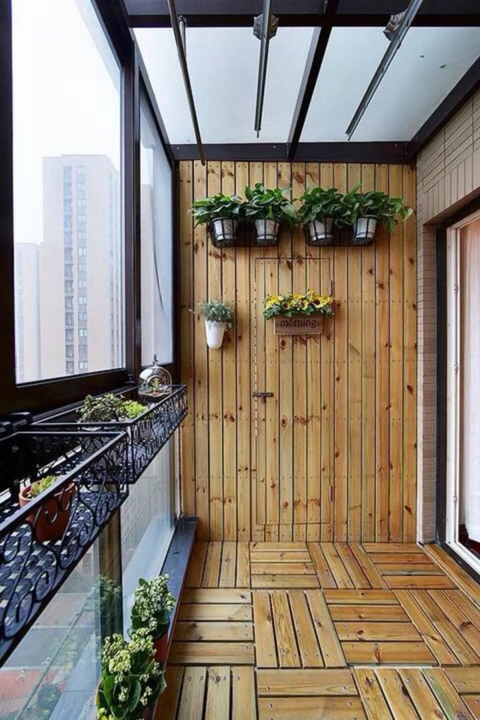 terrasse abritée avec revetement sol et murs en bois clair avec des pots suspendus