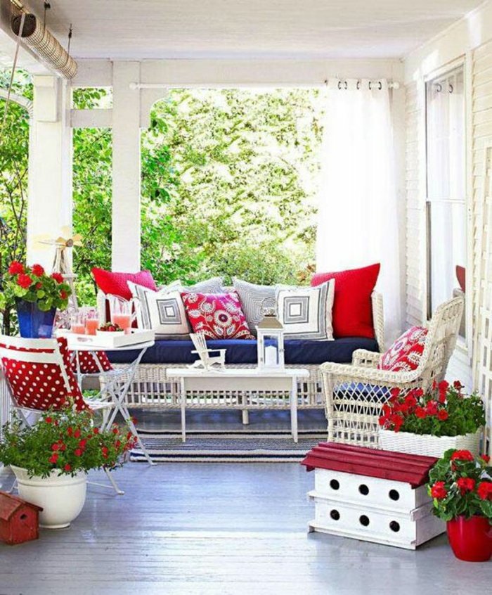 terrasses couvertes avec des meubles blancs de jardin et une multitude de coussins en rouge et blanc