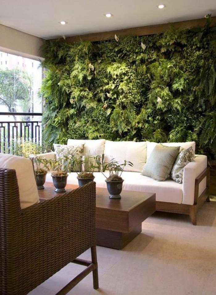 terrasses couvertes abritées avec un mur entier en plantes vertes avec plafond blanc et petits luminaires lumière discrète 