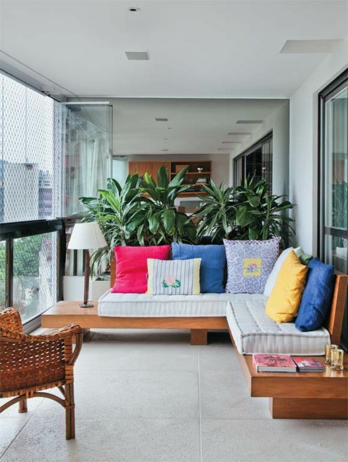 terrasse couverte avec des meubles en bois marron clair avec beaucoup de coussins multicolores