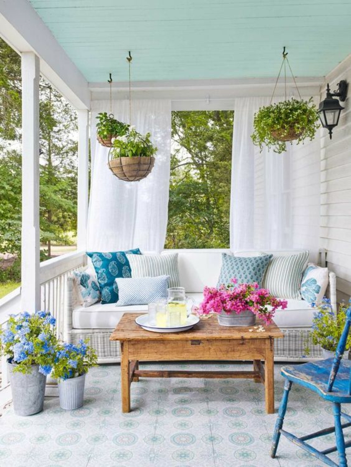 terrasse pergola veranda avec canapé en rotin blanc et des pots de plantes suspendus tressés
