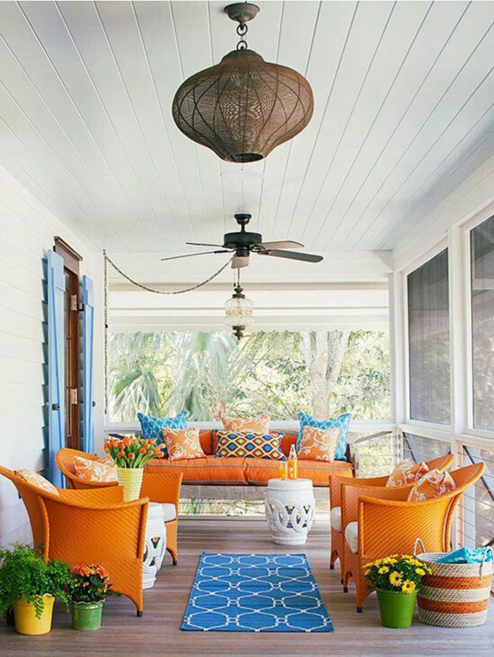 terrasse couverte avec des meubles en couleurs fruitées et un petit tapis bleu au centre