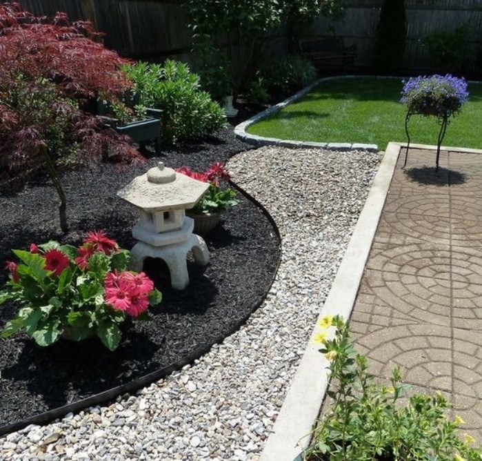 exemple de jardin zen minimaliste, coin japonais avec gravier et terreau, arbustes, arbres et lanterne en pierre, pelouse verte à coté