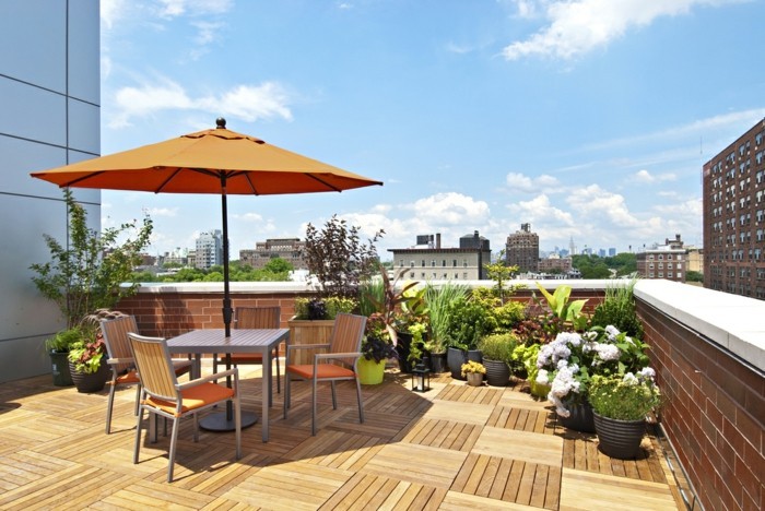 idée pour aménager sa terrasse sur le toit d un bâtiment, revêtement en bois, table et chaises grises, plantes dans des pots de fleurs gris, parasol orange
