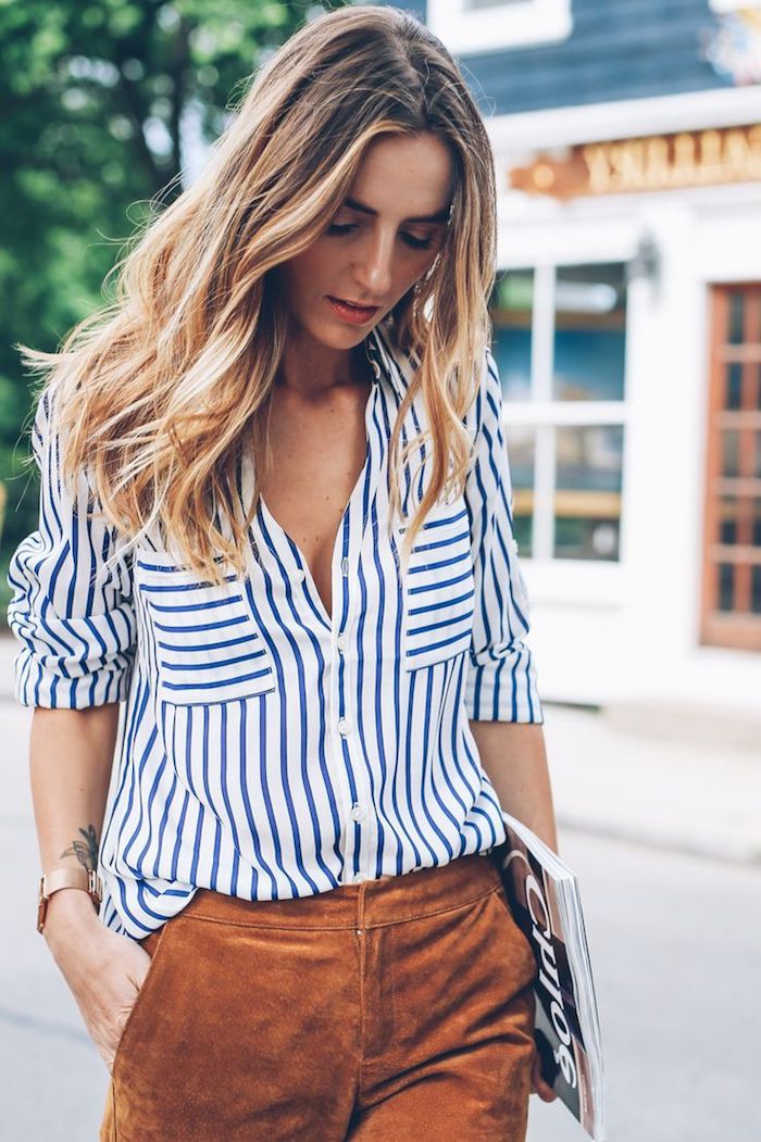 balayage-blond-pantalon-femme-en-marron-chemise-rayée-en-blanc-et-bleu-montre-en-or mèches blondes, promenade en ville femme, tatouage sur le bras femme, coupe de cheveux longs