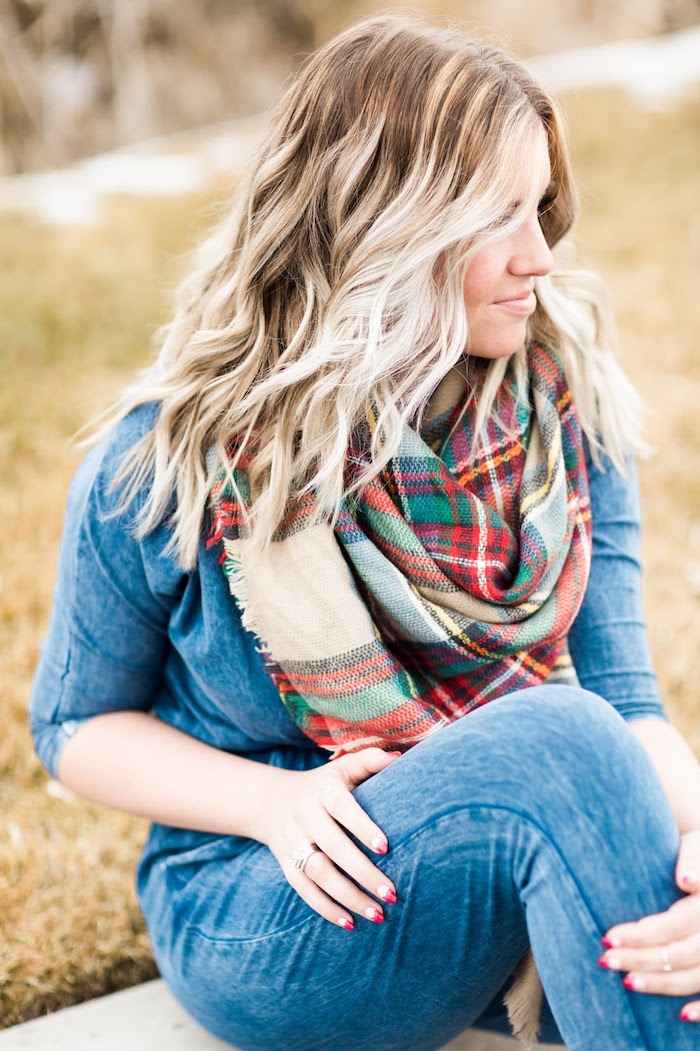 balayage-blond-sur-brune-manucure-française-en-rouge-écharpe-multicolore-avec-franges balayage sur cheveux chatain, chemise en denim, paire de jeans claires, femme aux cheveux bouclés