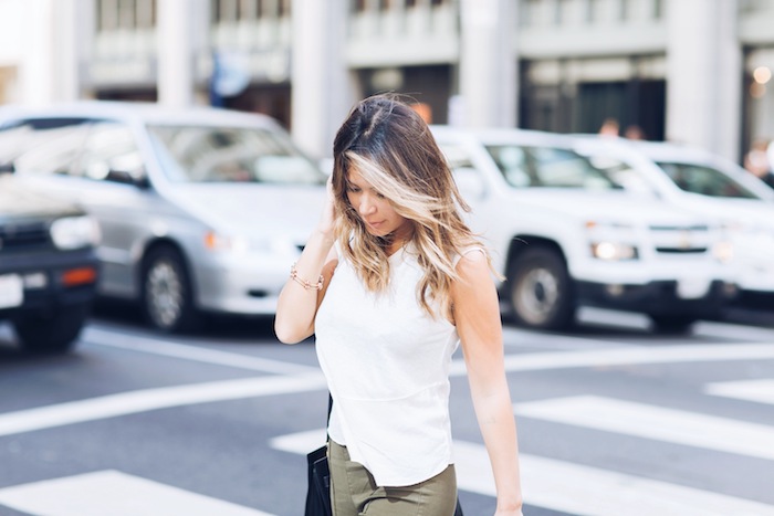 balayage-cheveux-pantalon-femme-khaki-débardeur-blanc-bracelet-en-or-sac-a-main-en-cuir-noir ombre hair, pantalon kaki modèle femme, sac à main avec poignée longue, coiffure cheveux lisses bouclés sur les pointes