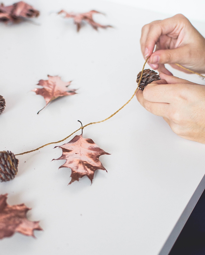 bricolage automne facile a realiser, une guirlande avec des feuilles d arbre naturelles décorées à la peinture couleur cuivre et pommes de pin