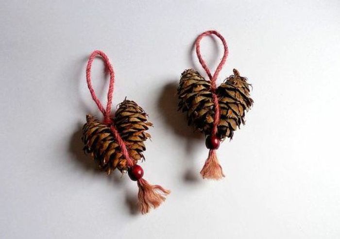 bricolage de noel facile, cones de pin attachés en forme de coeur et noués avec ficelle rouge
