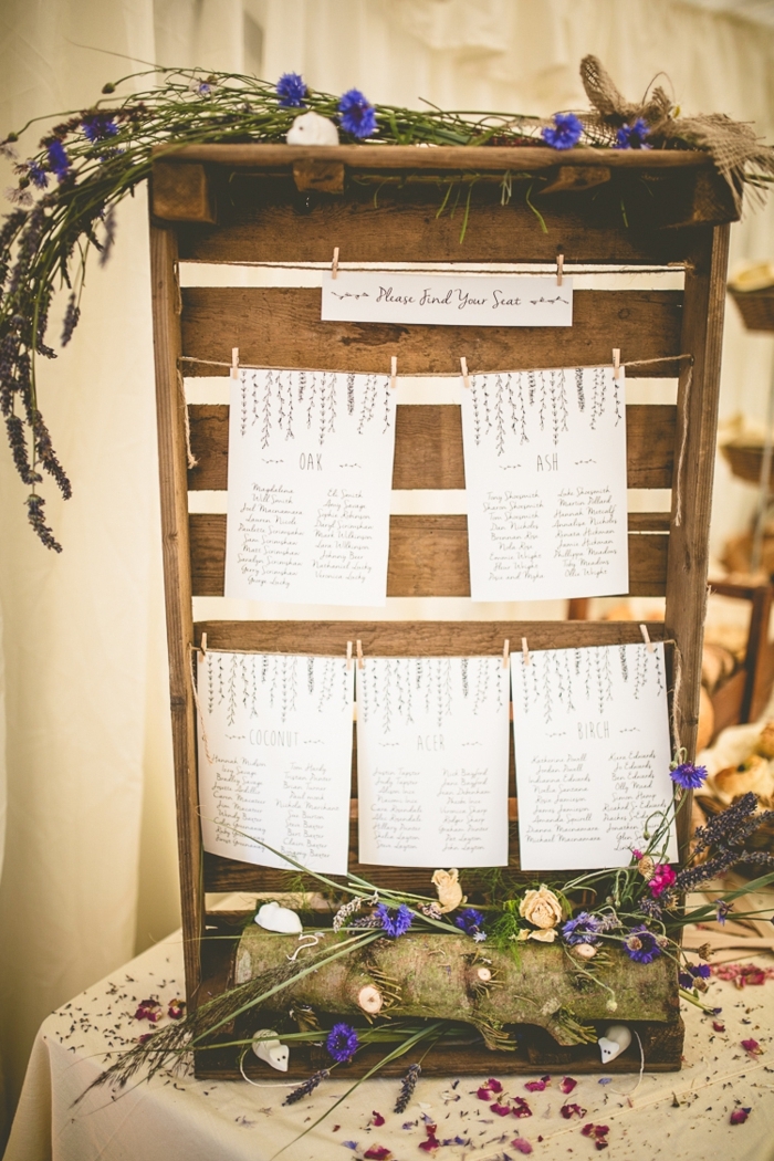 idée de decoration mariage champetre, deco cagette bois avec petites listes des invités par table et décoration de fleurs champêtres, bûche de bois