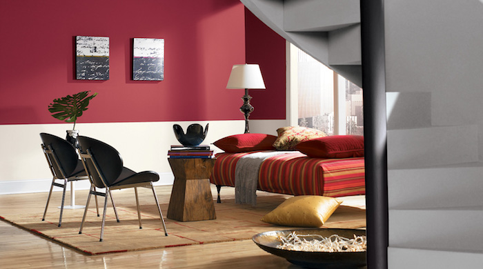 idee deco salon, pan de mur rouge bordeau, chaise longue rouge à rayures colorés, tapis beige, chaises noires, table basse en bois rustique