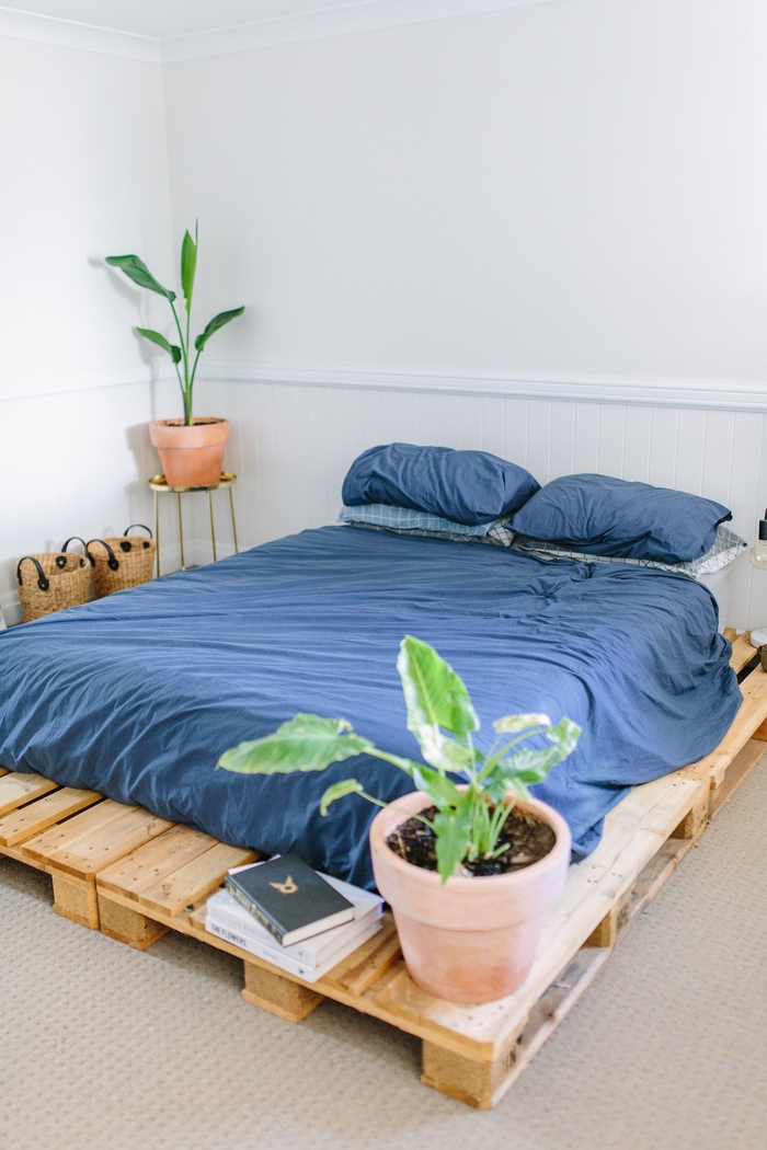 une ambiance intime et naturelle dans une chambre à coucher bohème chic à déco minimaliste de lit palette europe et des paniers de rangement en rotin