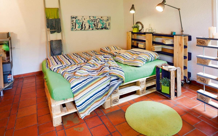 un sommier en palette et une tête de lit assortie en bois recyclé servant aussi d étagère 