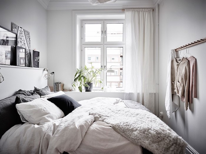 coussin scandinave, plusieurs coussins blancs et gris sur un lit avec linge de lit blanc, couverture moelleuse, decoration murale en art graphique
