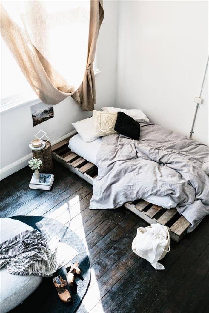 une chambre à coucher d'esprit récup avec un lit palette et une table de chevet en rondin de bois