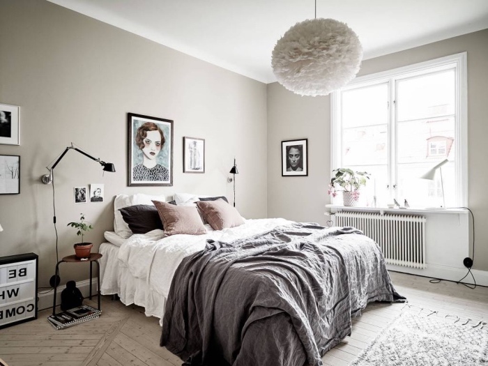 idée deco scandinave dans la chambre à coucher, linge de lit gris et blanc avec des coussins rose, parquet clair, tapis et mur gris, decoration portrait femme
