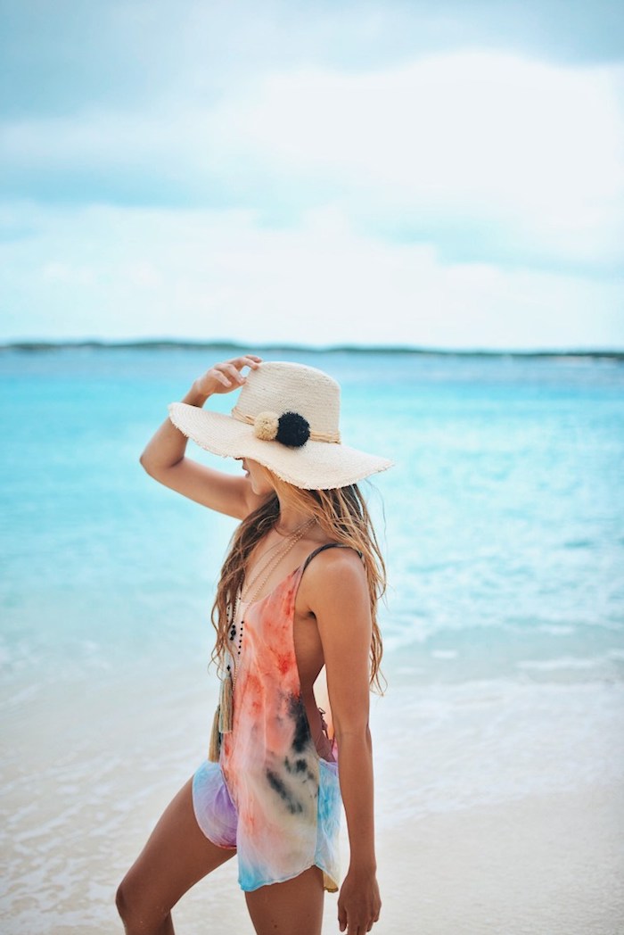 couleur-de-cheveux-tendance-capeline-beige-avec-corde-décoratifs-et-pompons-femme-plage-océan ombre hair, combishort multicolore avec bretelles noires, coupe de cheveux longs femme, coloration blonde sur base châtain