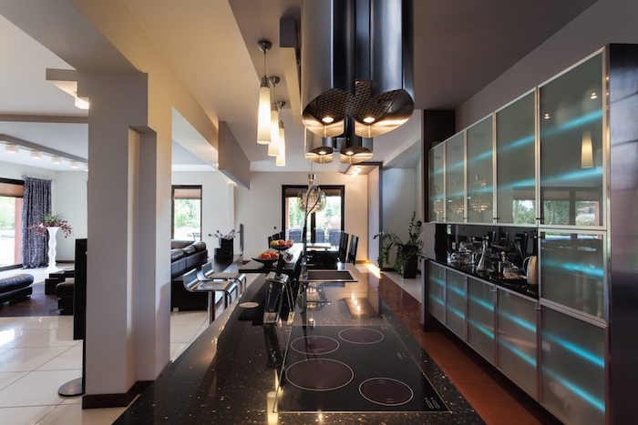 meuble haut cuisine, carrelage de sol en blanc, suspension luminaires en verre, comptoir noir avec plaques