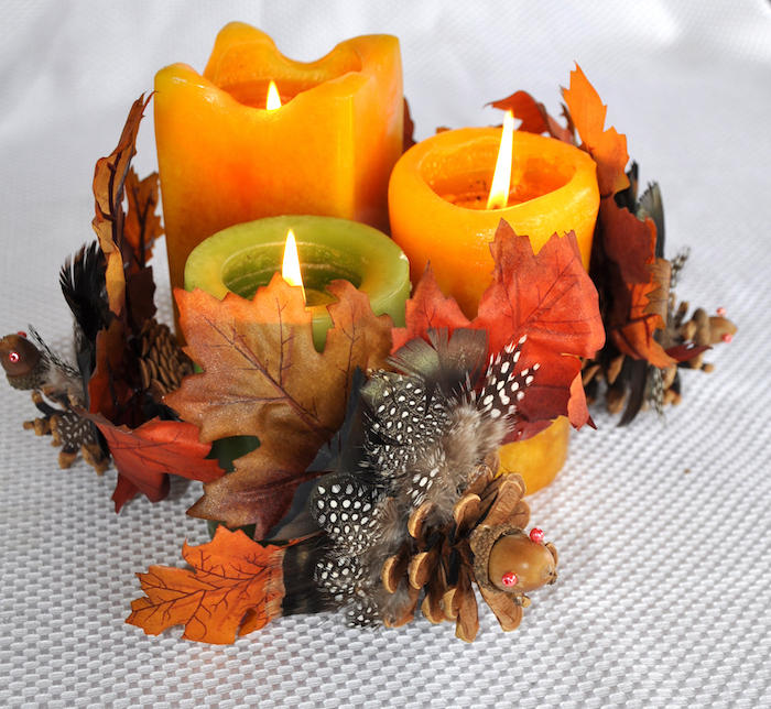 composition decorative de bougies colorées avec des feuilles d automne, pommes de pin et glands, deco automne a faire soi meme