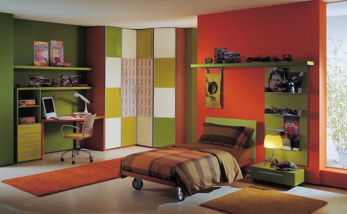 couleur complémentaire du rouge, mur d accent rouge tirant vers l orange, petit lit à roulettes, étagère verte, coin bureau mur vert, chaise enfant, amenagement chambre enfant