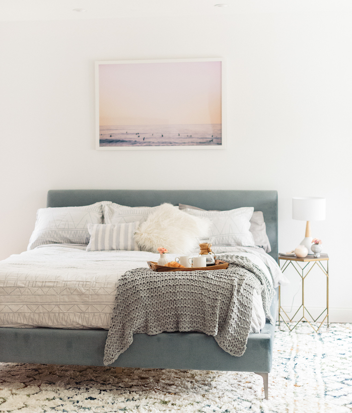idée déco chambre cocooning, tapis blanc à motifs géométriques, lit bleu pastel, linge de lit blanc et gris, plaid tricoté gris