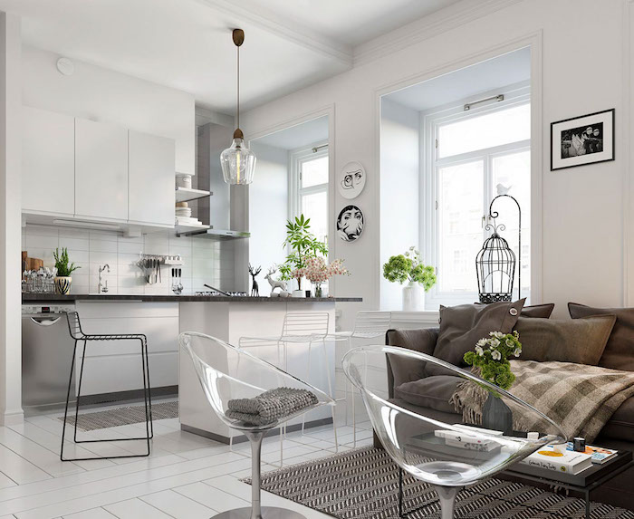 cuisine ouverte sur salon cocooning avec canapé et coussins gris, tapis noir et blanc, fauteuils transparentes, façade cuisine blanche