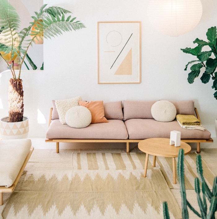 idee deco cocooning, canapé et table en bois, coussins d assise rose, tapis beige, plusieurs plantes exotiques vertes, suspension boule