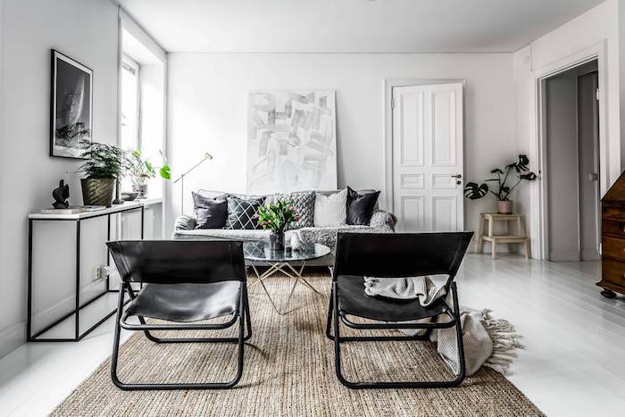 deco cocooning, canapé gris tapis beige chaises noires en cuir, murs blancs, parquet blanchi, table basse design, couverture grise enveloppante