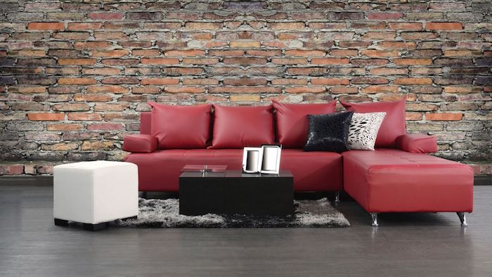 idée de canapé d angle couleur bordeau, revêtement sol et tapis gris, table basse noire, tabouret blanc, mur d accent en briques