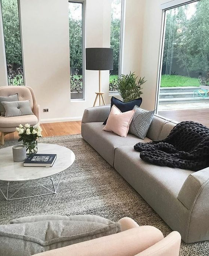 deco salon moderne, sofa gris, coussins déco en rose et gris, table ronde style scandinave, plaid au tricot noir