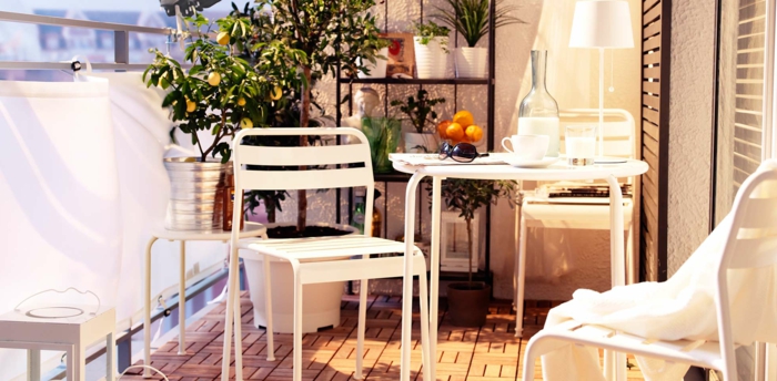 aménager une terrasse, petit balcon, chaises et table blanches metalliques, revêtement en bois, citronnier et autres plantes rangées sur une étagère noire
