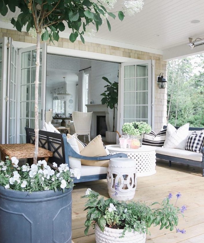 amenagement terrasse en bois, avec bancs en bois bleus, coussins noir et blanc, table basse orientale, plantes et fleurs
