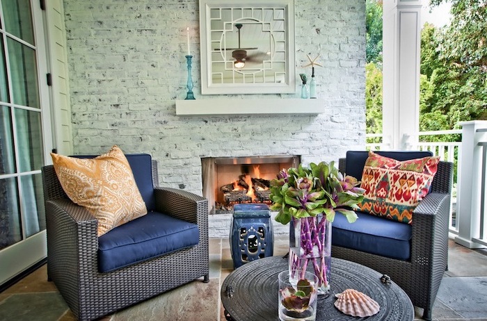 deco terrasse zen avec revêtement carrelage, fauteuils tressés, coussins d assise bleus, table basse design, coussins orientaux, cheminée exterieure, mur de briques blanchies