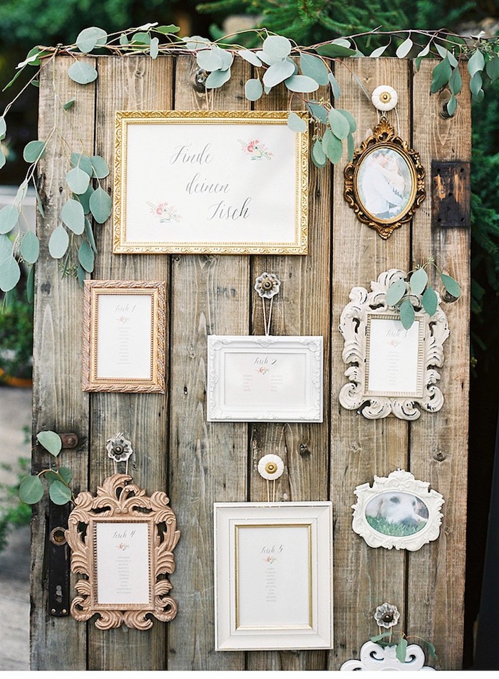 plan de table mariage en plein air, des planches de bois brut assemblées et cadres photo vintage avec prénoms invités, petite décoration verte