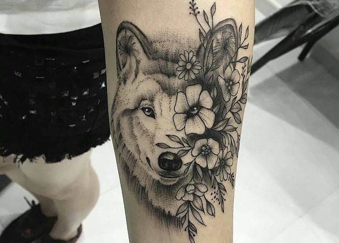 tatouage loup femme, tête de loup avec fleurs sur le bras, dessin en encre modèle feminin