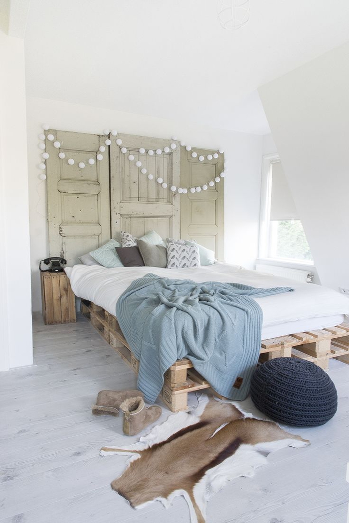 une chambre à coucher accueillante de style scandinave qui adopte la tendance récup avec un lit en palette europe et une têtê de lit en porte ancienne