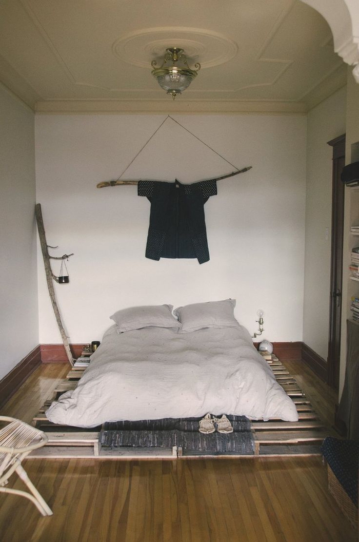 une déco de chambre à coucher récup et minimaliste avec un sommier en palette de bois et des branches de bois détournées en objets déco