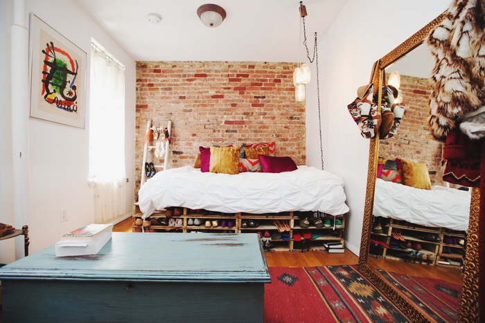 aménagement intelligent d une petite chambre à coucher bohème chic avec un grand miroir adossé au mur et un lit palette avec espace de rangement